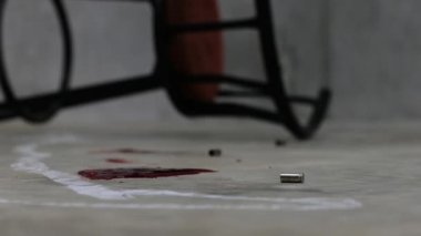 Adli tıp müfettişi olay yerindeki bir silahın fişeklerini vurguluyor.