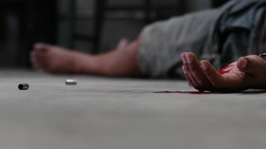 Adli tıp müfettişi olay yerindeki bir silahın fişeklerini vurguluyor.