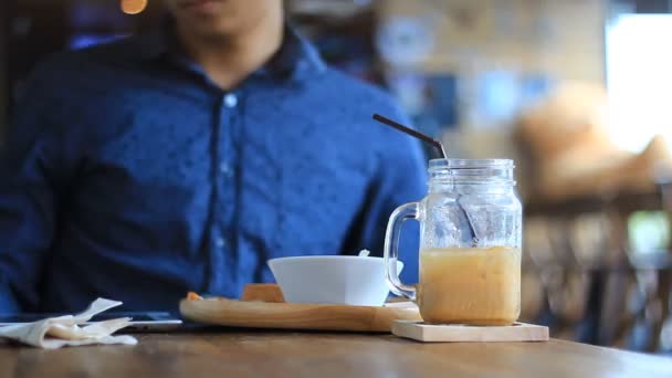 Hombre joven con Tablet PC beber café en la cafetería — Vídeos de Stock