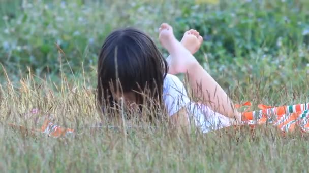 Κορίτσι με μια οθόνη αφής που βρίσκεται στο γρασίδι στο ηλιοβασίλεμα φώτα — Αρχείο Βίντεο
