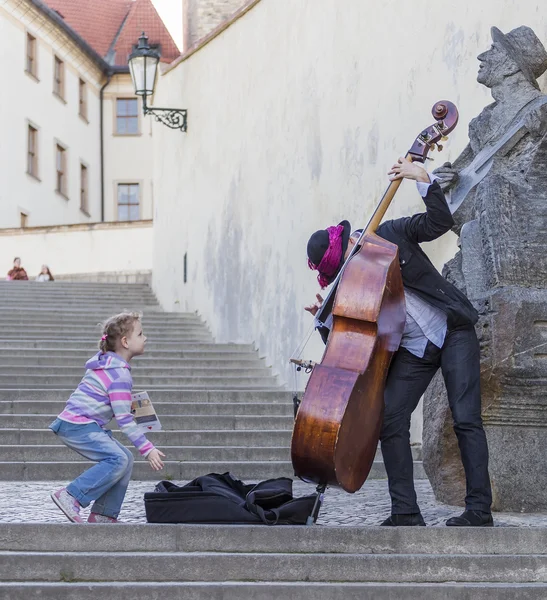 A girl throws a coin street musician in gratitude for his music — Stock Photo, Image