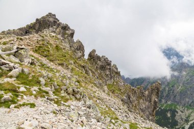 Slovakya, yüksek Tatra dağlarındaki kayalık dağların zirveler arasında hareket eden bulutlarla kaplı dağlık bir manzaradır.