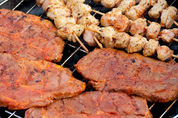 Closeup view of barbecue skewers and grill steaks on a grill — Stock Photo, Image