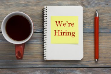 İşe alıyoruz. Not defteri, kalem ve coffe fincan ile Ofis masası masa. Üstte görüntü.