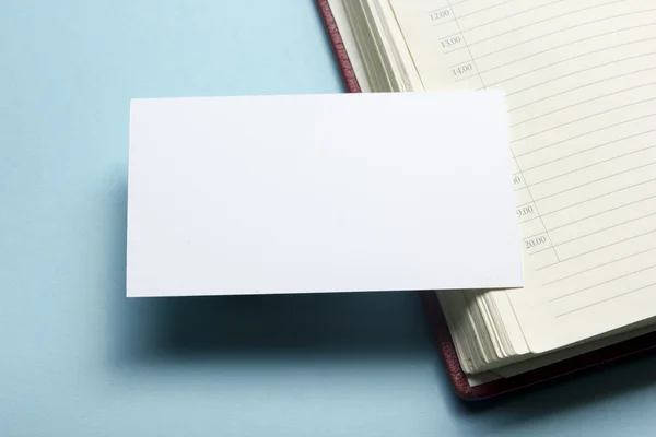 Business card blank over notepad at office table. Corporate stationery branding mock-up