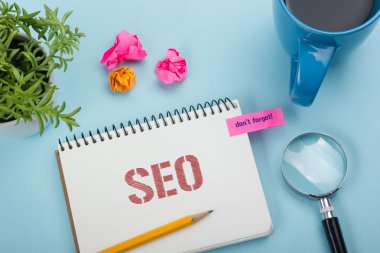 Seo, online kavram. Mesaj, kalem, kahve fincanı ve çiçek ile Not Defteri. Masa üstü görünümünde ofis malzemeleri