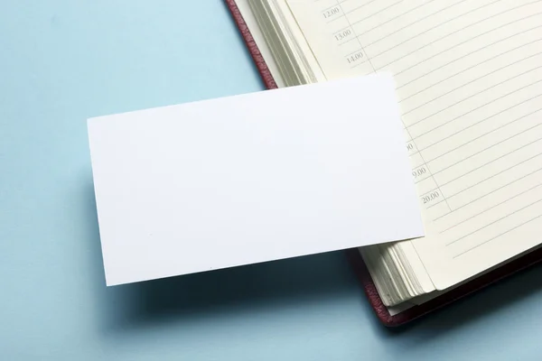 Tarjeta de visita en blanco sobre bloc de notas en la mesa de la oficina. Maqueta de marca de papelería corporativa — Foto de Stock