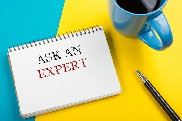 Ask an expert. Notepad with message, pen and coffee cup. Office supplies on desk table top view. — Stock Photo, Image