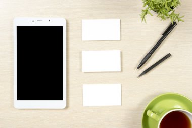 Boş kartvizit, smartphone ya da tablet pc, çiçek, kahve fincanı ve ofis Resepsiyon Masa üstü, kalem görüntüleyin. Kurumsal ileti örneği marka model