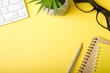 Laptop, akıllı telefon ve bir fincan kahveli diğer iş gereçleri olan sarı masa ofisi. Metni kopyalamak için üst görünümü kullan. Desenci çalışma alanı düz masa üzerinde temel elementler yatıyordu