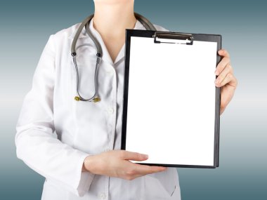 Female doctor's hand holding blank medical clipboard and stethoscope on blurred background. Concept of Healthcare And Medicine. Copy space.