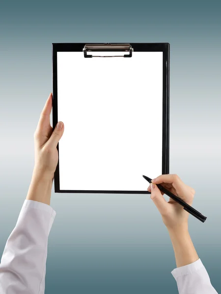 A female hand holding a pen and clipboard with blank paper (document, report) on blurred background. Top view. — ストック写真