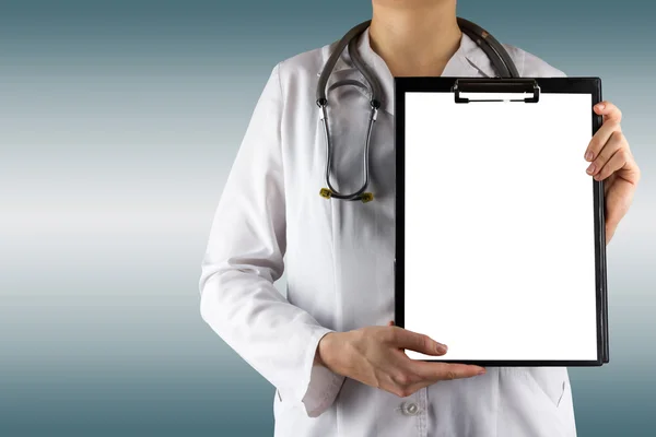 Female doctor's hand holding blank medical clipboard and stethoscope on blurred background. Concept of Healthcare And Medicine. Copy space. — Φωτογραφία Αρχείου