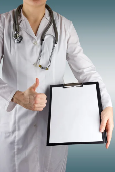 Female doctor's hand holding medical clipboard with blank sheet of paper and stethoscope, giving thumbs up success sign on blurred background. Concept of Healthcare And Medicine. Copy space — Φωτογραφία Αρχείου