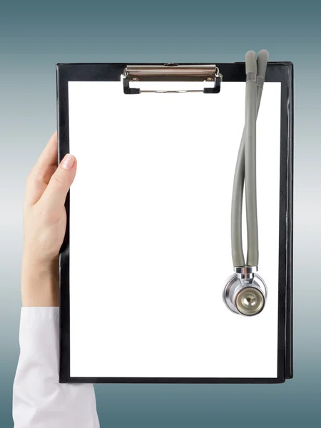 Female doctor's hand holding blank medical clipboard and stethoscope on blurred background. Concept of Healthcare And Medicine. Copy space. Stock Photo