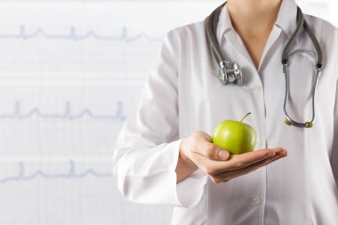 Yeşil elma tutan kadın doktorun el. Tıbbi arka plan bulanık vuruşta kapatın. Sağlık ve tıp kavramı. Kopya alanı