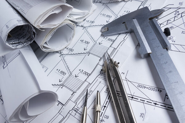 Architectural project, blueprints, blueprint rolls and divider compass, calipers on vintage wooden background. Construction concept. Engineering tools. Copy space