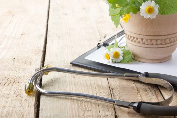 Fresh herb, medical clipboard and stethoscope on wooden table. Alternative medicine concept. — Stock fotografie