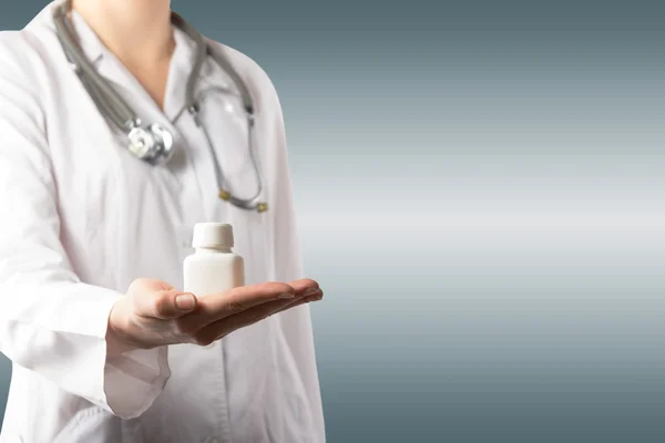Médico femenino sosteniendo un frasco de tabletas o pastillas con un bla — Foto de Stock