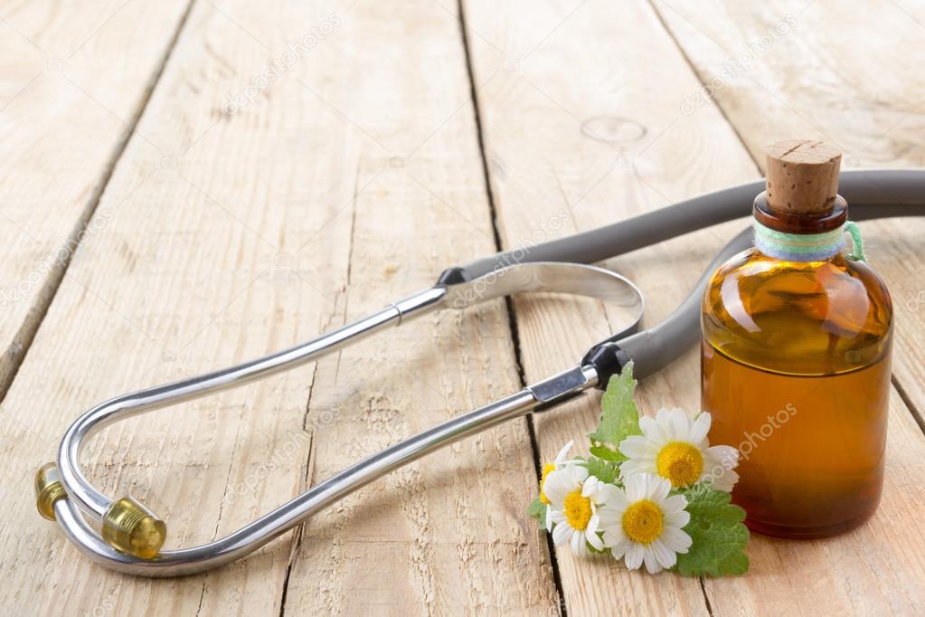 Fresh herb and stethoscope on wooden table. Alternative medicine concept.