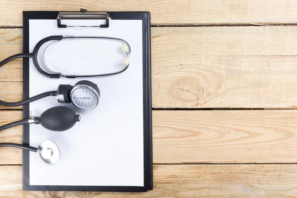 Lieu de travail d'un médecin. Tablette, stéthoscope, stylo noir sur fond de bureau en bois. Vue du dessus — Photo