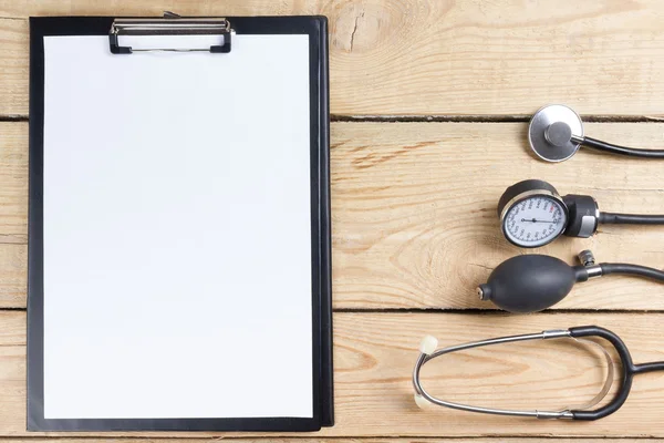 Lieu de travail d'un médecin. Tablette, stéthoscope, stylo noir sur fond de bureau en bois. Vue du dessus — Photo