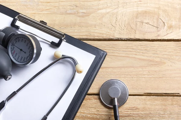 Lieu de travail d'un médecin. Tablette, stéthoscope, stylo noir sur fond de bureau en bois. Vue du dessus — Photo