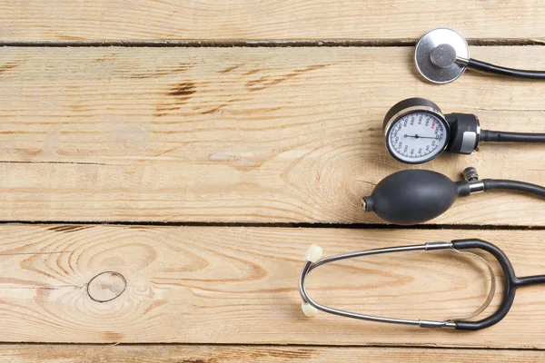 Lugar de trabajo de un médico. Tableta, estetoscopio, bolígrafo negro sobre fondo de escritorio de madera. Vista superior —  Fotos de Stock