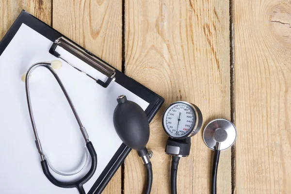 Luogo di lavoro di un medico. Compressa, stetoscopio, penna nera su fondo scrivania in legno. Vista dall'alto — Foto Stock