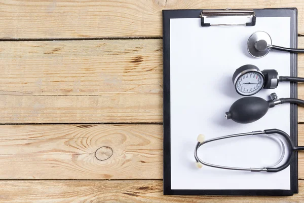 Lieu de travail d'un médecin. Tablette, stéthoscope, stylo noir sur fond de bureau en bois. Vue du dessus — Photo