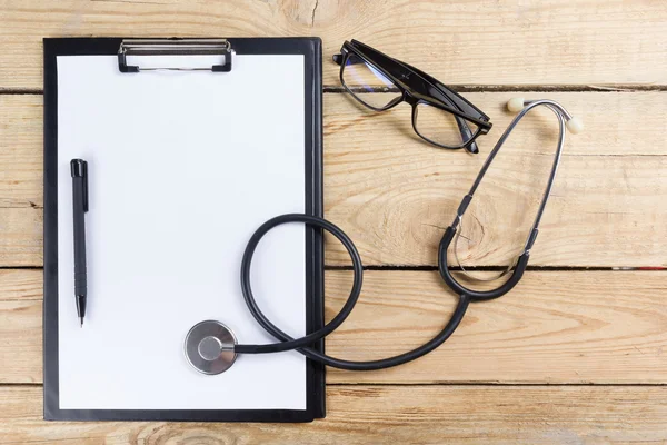 Luogo di lavoro di un medico. Compressa, stetoscopio, penna nera su fondo scrivania in legno. Vista dall'alto — Foto Stock