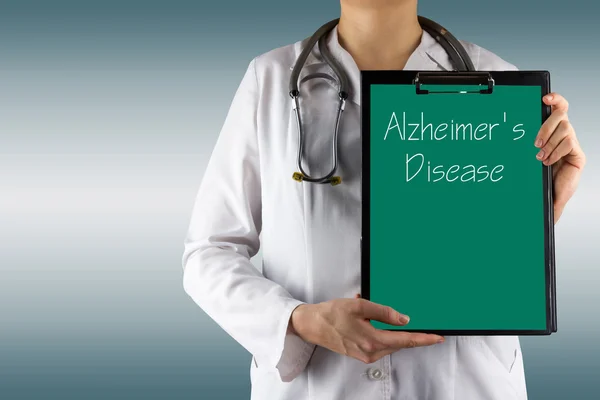 Болезнь Альцгеймера - женская рука врача с медицинским планшетом и стетоскопом — стоковое фото