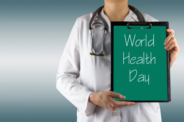 World Health Day - Female doctor's hand holding medical clipboard and stethoscope — Stock Photo, Image