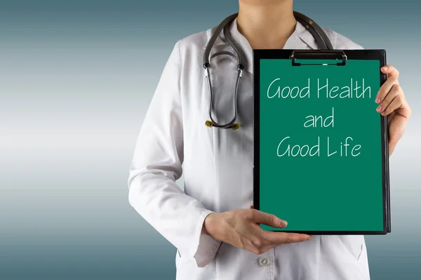 Buena salud y buena vida - La mano de la doctora sosteniendo el portapapeles médico y el estetoscopio —  Fotos de Stock