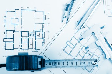 Architectural project, blueprints, blueprint rolls and divider compass, calipers, folding ruler on plans Engineering tools view from the top. Copy space. Construction background. Blue toned