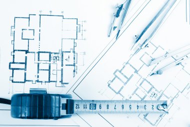 Architectural project, blueprints, blueprint rolls and divider compass, calipers, folding ruler on plans Engineering tools view from the top. Copy space. Construction background. Blue toned