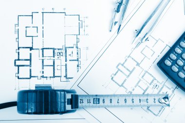 Architectural project, blueprints, blueprint rolls and divider compass, calipers, folding ruler on plans Engineering tools view from the top. Copy space. Construction background. Blue toned