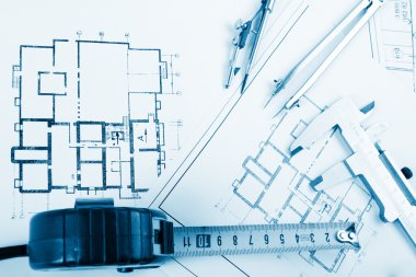 Architectural project, blueprints, blueprint rolls and divider compass, calipers, folding ruler on plans Engineering tools view from the top. Copy space. Construction background. Blue toned