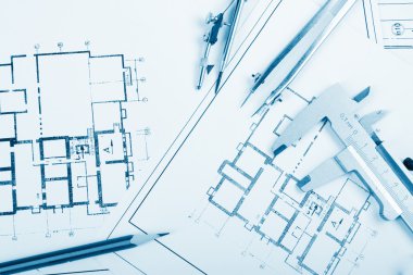 Architectural project, blueprints, blueprint rolls and divider compass, calipers, folding ruler on plans Engineering tools view from the top. Copy space. Construction background. Blue toned
