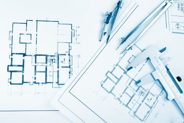 Architectural project, blueprints, blueprint rolls and divider compass, calipers, folding ruler on plans Engineering tools view from the top. Copy space. Construction background. Blue toned