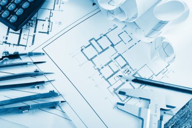 Architectural project, blueprints, blueprint rolls and divider compass, calipers, folding ruler on plans Engineering tools view from the top. Copy space. Construction background. Blue toned