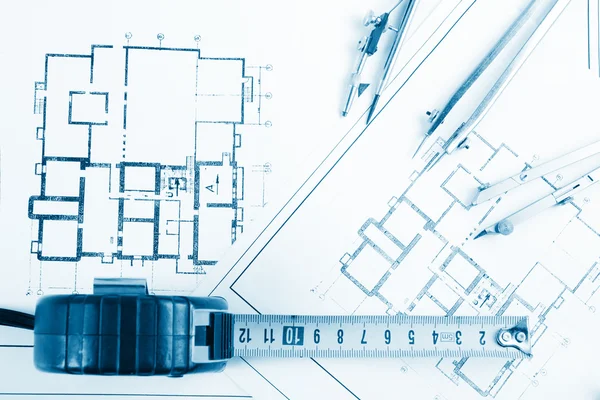 Architectural project, blueprints, blueprint rolls and divider compass, calipers, folding ruler on plans Engineering tools view from the top. Copy space. Construction background. Blue toned