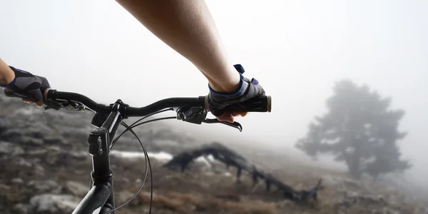 Hands in gloves holding handlebar of a bicycle. Mountain Bike cyclist riding single track. Healthy lifestyle active athlete doing sport — Stock Photo, Image