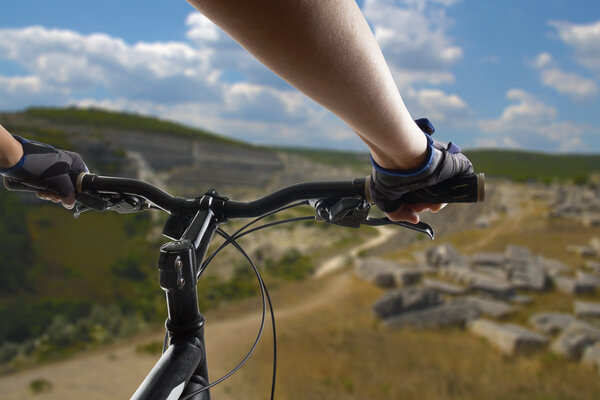 Hands in gloves holding handlebar of a bicycle. Mountain Bike cyclist riding single track. Healthy lifestyle active athlete doing sport