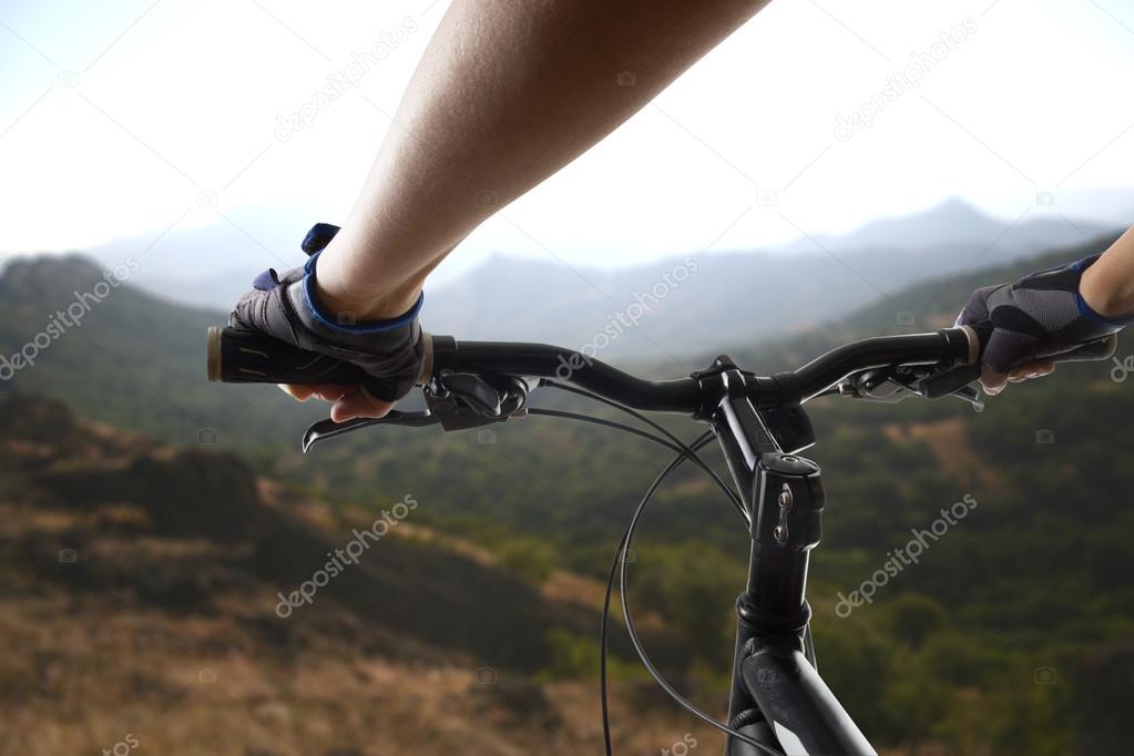 Hands in gloves holding handlebar of a bicycle. Mountain Bike cyclist riding single track. Healthy lifestyle active athlete doing sport