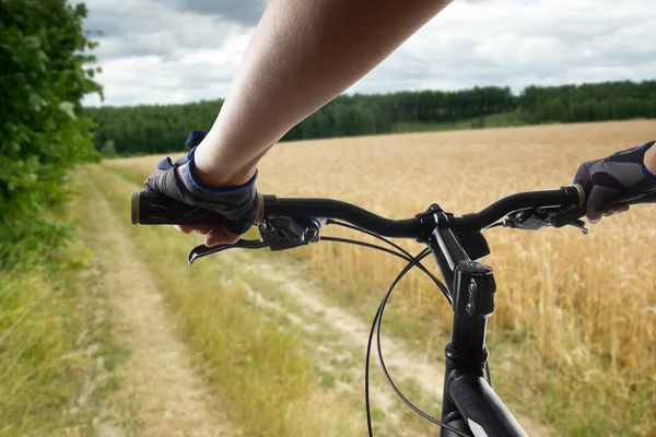 Manos en guantes sosteniendo el manillar de una bicicleta. Bicicleta de montaña ciclista montar una sola pista. Estilo de vida saludable atleta activo haciendo deporte — Foto de Stock