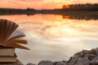 Kitap ve bulanık doğa manzara fonunda günbatımı gökyüzü arka ışık açık ciltli kitap yığını. Alan, okula geri kopyalayın. Eğitim arka plan.