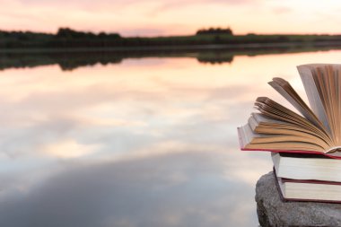 Kitap ve bulanık doğa manzara fonunda günbatımı gökyüzü arka ışık açık ciltli kitap yığını. Alan, okula geri kopyalayın. Eğitim arka plan.