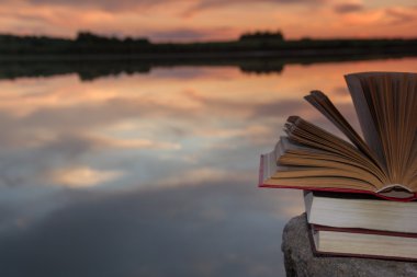 Kitap ve bulanık doğa manzara fonunda günbatımı gökyüzü arka ışık açık ciltli kitap yığını. Alan, okula geri kopyalayın. Eğitim arka plan.