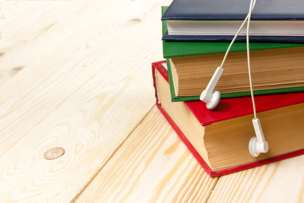 Ahşap masa ve kulaklık renkli kitap yığını. Audiobook kavramı